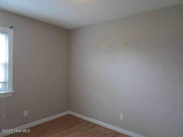 empty room featuring wood finished floors and baseboards
