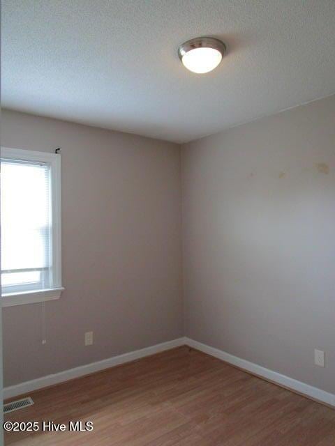 unfurnished room with light wood-style flooring, baseboards, and visible vents