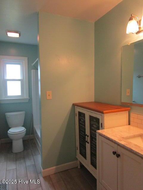 full bath featuring toilet, vanity, baseboards, and wood finish floors