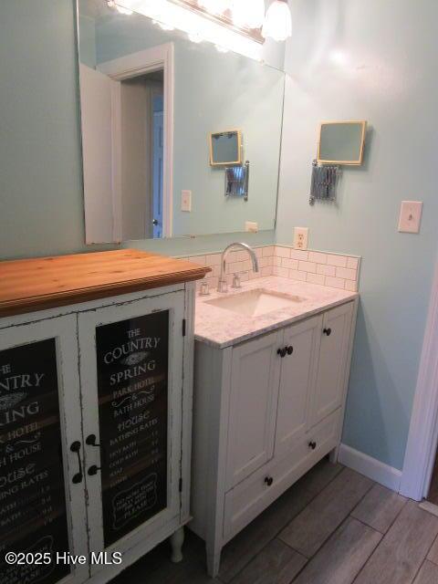 bathroom with wood finished floors, vanity, and baseboards