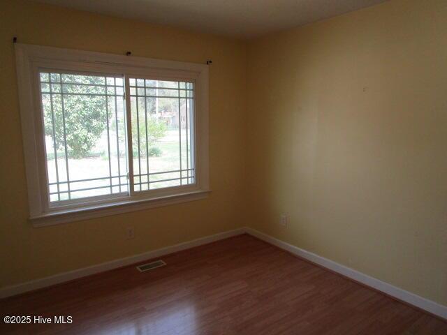 spare room featuring wood finished floors, baseboards, and visible vents
