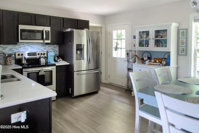314 Nugget Trl, Elizabeth City, NC 27909 - kitchen featuring appliances with stainless steel finishes, light countertops, light wood finished floors, backsplash, and glass insert cabinets
