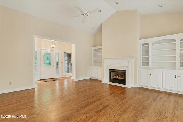 17 Windsong Pl, Whispering Pines, NC 28327 - unfurnished living room featuring high vaulted ceiling, ceiling fan, light wood-style flooring, and a fireplace with flush hearth