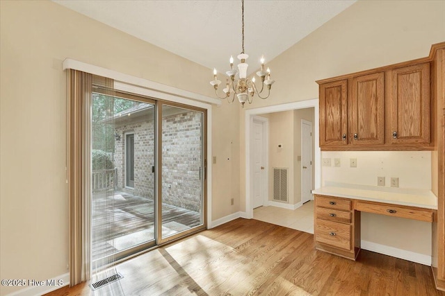 17 Windsong Pl, Whispering Pines, NC 28327 - unfurnished dining area with lofted ceiling, a chandelier, light wood-type flooring, and built in desk