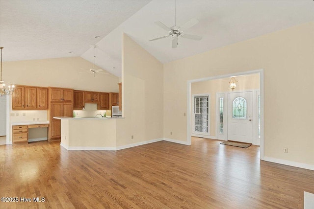 17 Windsong Pl, Whispering Pines, NC 28327 - unfurnished living room featuring a ceiling fan, high vaulted ceiling, a chandelier, and light wood-style flooring