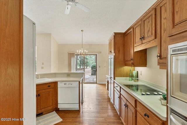 17 Windsong Pl, Whispering Pines, NC 28327 - kitchen with dishwasher, electric stovetop, brown cabinets, a chandelier, and light countertops