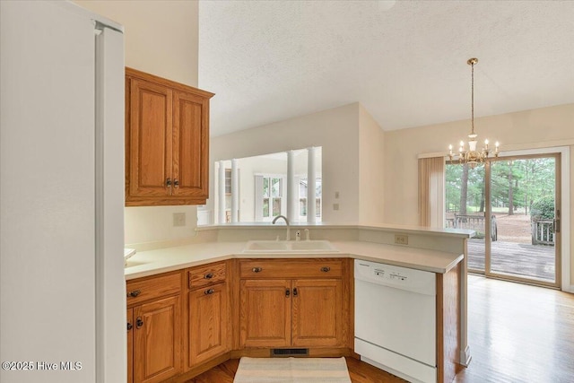 17 Windsong Pl, Whispering Pines, NC 28327 - kitchen with white appliances, a chandelier, a peninsula, light countertops, and a textured ceiling
