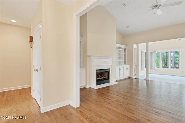 17 Windsong Pl, Whispering Pines, NC 28327 - unfurnished living room with ceiling fan, light wood finished floors, a fireplace with flush hearth, decorative columns, and lofted ceiling