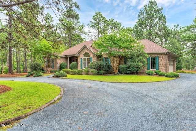 17 Windsong Pl, Whispering Pines, NC 28327 - ranch-style house featuring curved driveway, brick siding, a front yard, and a garage