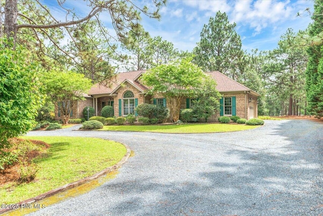 17 Windsong Pl, Whispering Pines, NC 28327 - view of front of home with curved driveway, brick siding, and a front yard