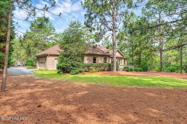 17 Windsong Pl, Whispering Pines, NC 28327 - back of house featuring brick siding, an attached garage, driveway, and a yard