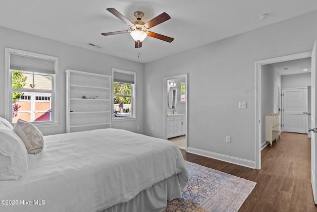 bedroom with multiple windows, wood finished floors, baseboards, and connected bathroom