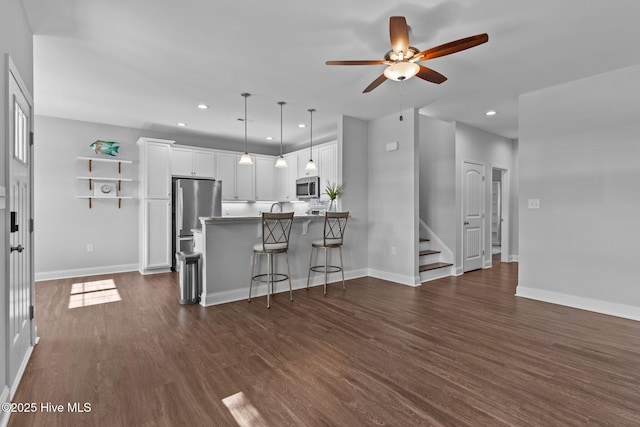 living room featuring a ceiling fan, dark wood finished floors, baseboards, recessed lighting, and stairway