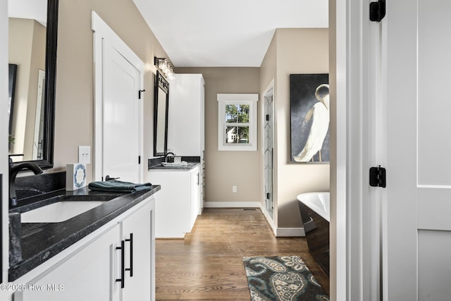 6445 Red Oak Rd, Battleboro, NC 27809 - bathroom featuring two vanities, wood finished floors, a freestanding tub, and a stall shower
