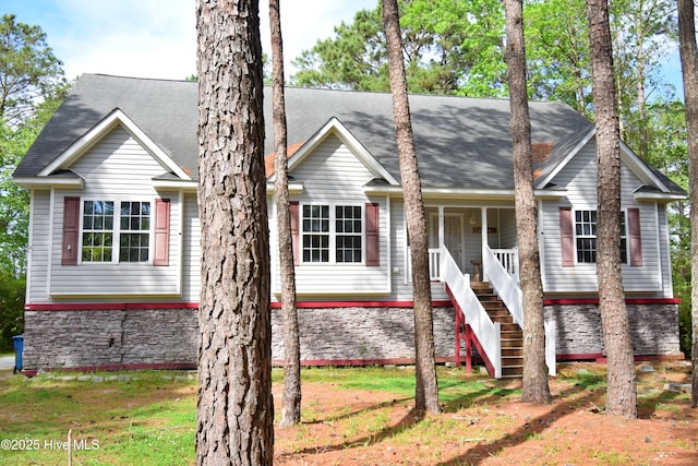 view of front of home with roof with shingles, stone siding, stairs, and a porch