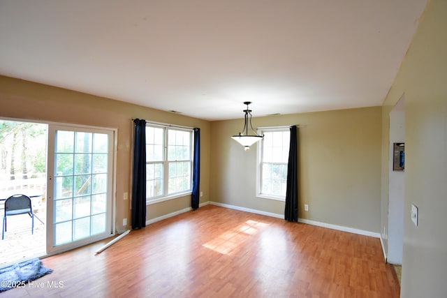 empty room with light wood finished floors, plenty of natural light, and baseboards