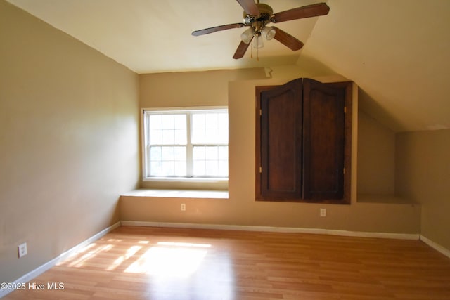 interior space with light wood-style flooring, baseboards, vaulted ceiling, and a ceiling fan