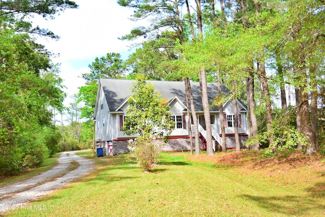 view of front of property with stairway, dirt driveway, and a front yard