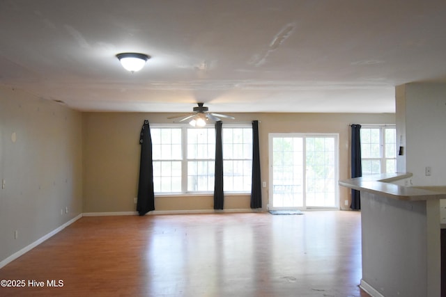 empty room with ceiling fan, baseboards, and wood finished floors