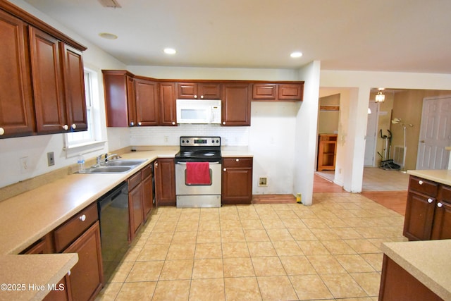 kitchen with light countertops, dishwasher, a sink, white microwave, and stainless steel electric range oven
