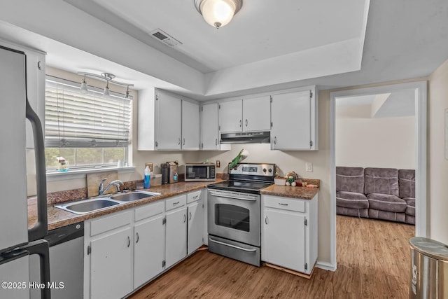 213 Spruce Ct, Jacksonville, NC 28546 - kitchen featuring appliances with stainless steel finishes, a sink, under cabinet range hood, wood finished floors, and white cabinets