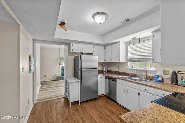 213 Spruce Ct, Jacksonville, NC 28546 - kitchen with appliances with stainless steel finishes, a sink, wood finished floors, a raised ceiling, and baseboards