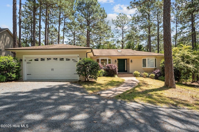 ranch-style house featuring an attached garage and gravel driveway