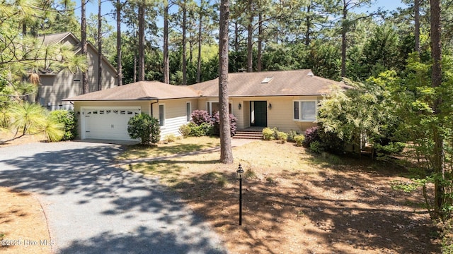 ranch-style home with an attached garage, driveway, and roof with shingles