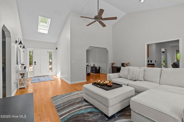 living room featuring visible vents, ceiling fan, light wood-type flooring, arched walkways, and vaulted ceiling
