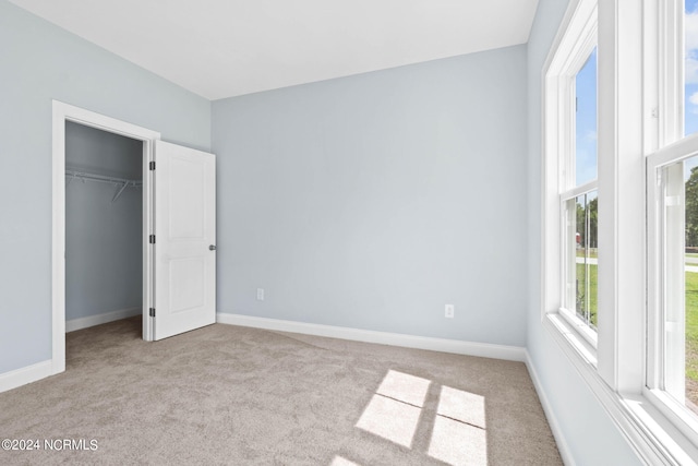unfurnished bedroom featuring light carpet, baseboards, and a closet