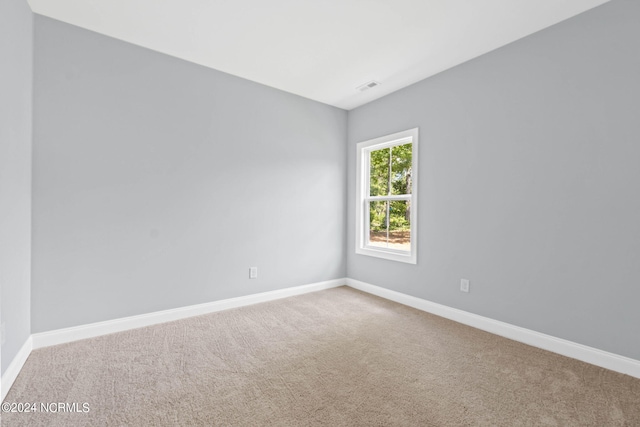 carpeted spare room featuring visible vents and baseboards