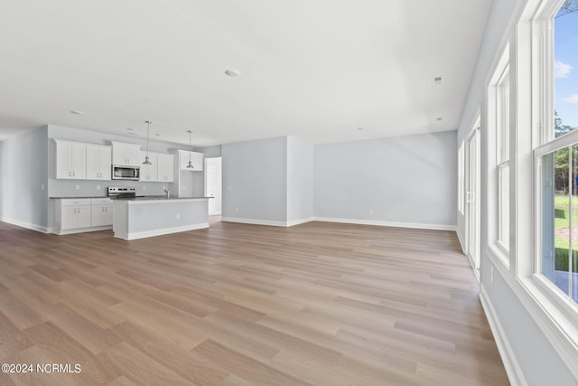 unfurnished living room with light wood finished floors and baseboards