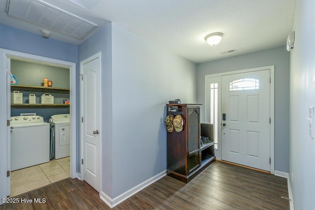 foyer entrance featuring visible vents, baseboards, wood finished floors, and washer and dryer