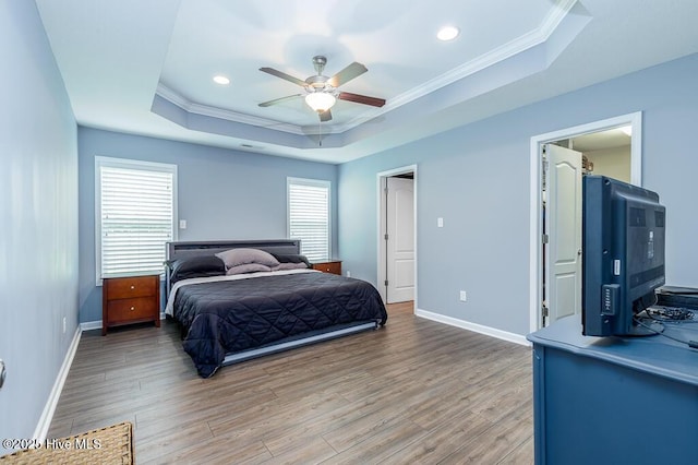 bedroom featuring crown molding, baseboards, a tray ceiling, and light wood-type flooring