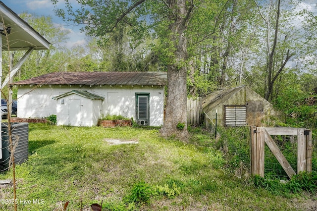 exterior space featuring fence, a gate, an outdoor structure, and a yard
