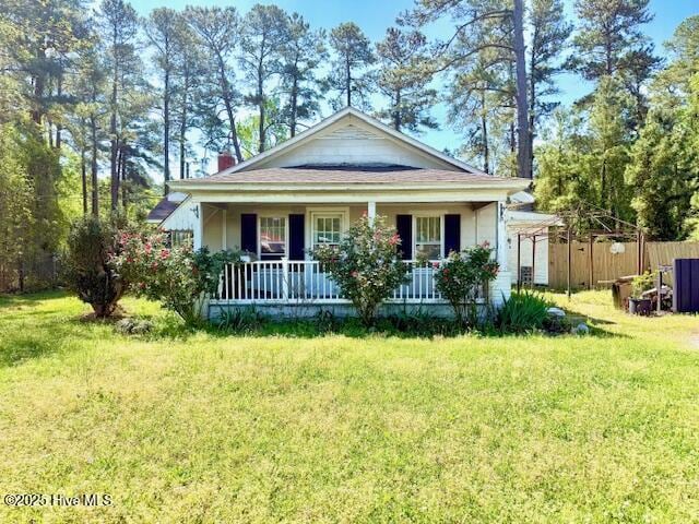 bungalow-style house with fence, a front lawn, and covered porch