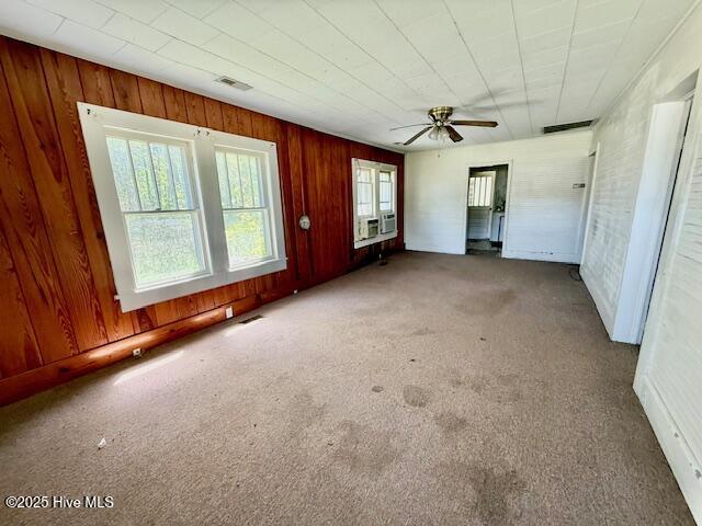 interior space featuring wood walls, visible vents, cooling unit, and ceiling fan