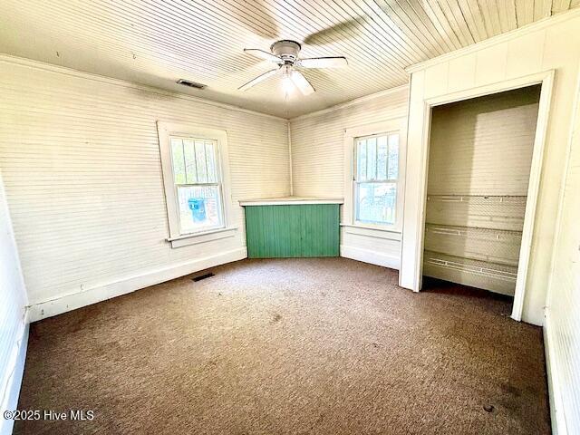 unfurnished bedroom with a ceiling fan, visible vents, ornamental molding, and carpet