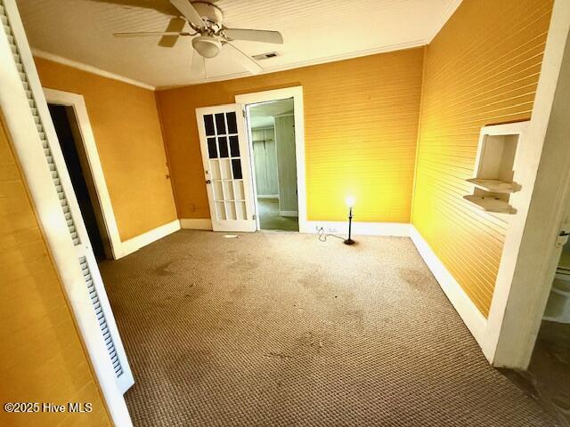 unfurnished bedroom featuring ceiling fan, ornamental molding, visible vents, carpet floors, and baseboards