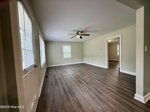 spare room with baseboards, a ceiling fan, and dark wood finished floors