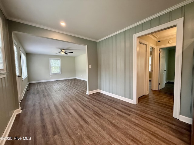 spare room with dark wood-type flooring, baseboards, ornamental molding, and a ceiling fan