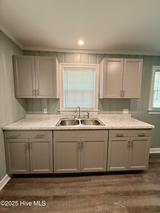 kitchen with baseboards, ornamental molding, gray cabinetry, dark wood-type flooring, and a sink