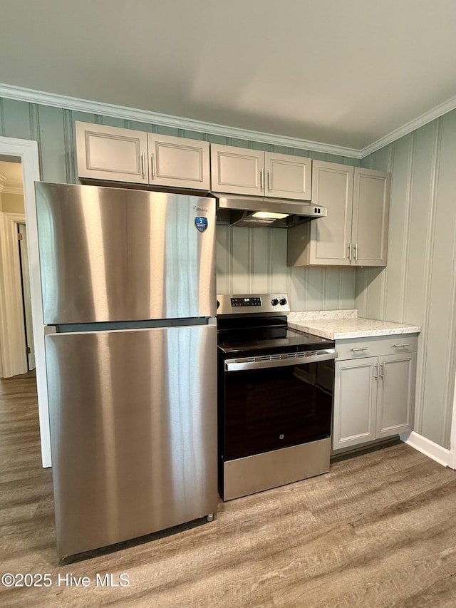 kitchen featuring crown molding, light wood-type flooring, appliances with stainless steel finishes, and under cabinet range hood