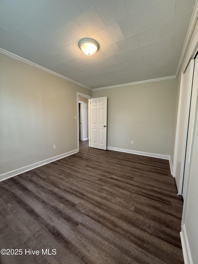 unfurnished bedroom featuring dark wood-type flooring, ornamental molding, and baseboards