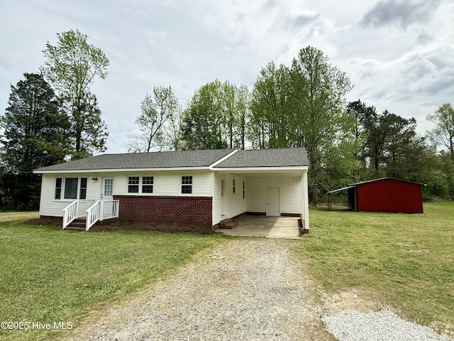 single story home with driveway, a front yard, an attached carport, and an outdoor structure