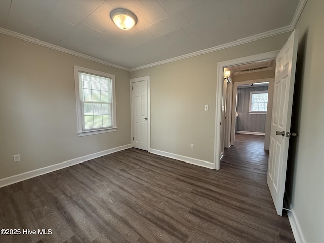 unfurnished room featuring crown molding, attic access, baseboards, and dark wood-style floors
