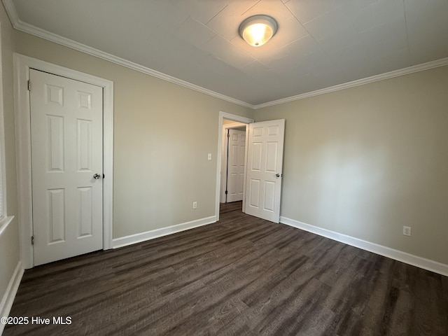 unfurnished bedroom featuring dark wood-style flooring, baseboards, and crown molding