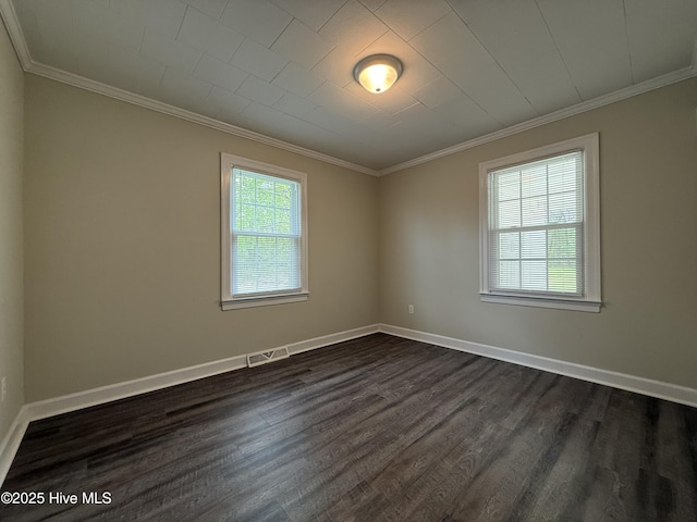 empty room featuring crown molding, baseboards, dark wood finished floors, and visible vents