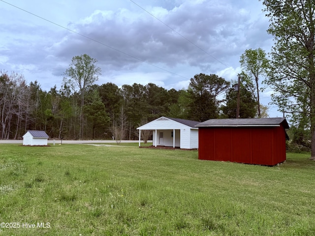 view of yard featuring a storage shed, a view of trees, and an outdoor structure
