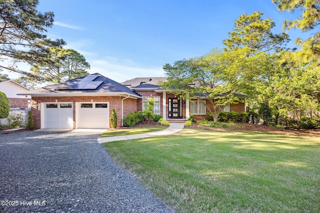 120 Clay Cir W, End, NC 27376 - view of front of house with gravel driveway, a front yard, a garage, solar panels, and brick siding